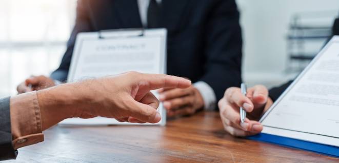 Business partners reviewing contract terms and conditions during a meeting, pointing finger at important clauses