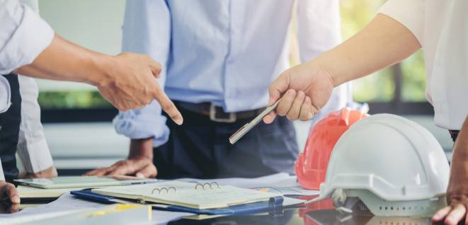 Contractor and engineer with blueprints discuss at a modern construction site