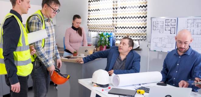 The head of a construction company chastises his workers in green vests