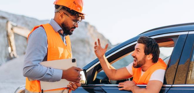 Angry bearded man sitting in modern car yelling at colleague on mining site. Conflict, problem